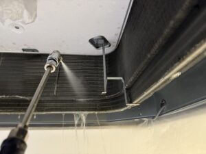 専用のポリッシャー（洗浄機）を使用して床面を洗浄している作業風景。蓄積した古いワックスと汚れが洗剤でドロドロに浮き上がり、泡立っている様子