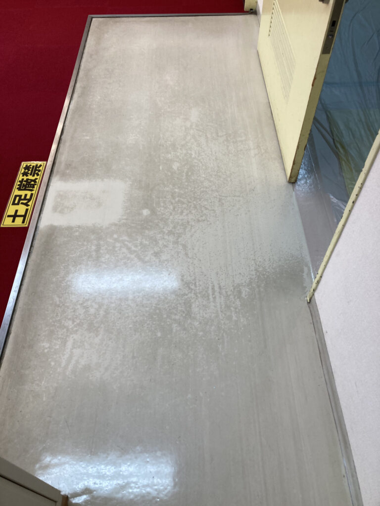京都市のホール楽屋床の剥離洗浄テスト。張替えが必要に見えるほど黒ずんだ長尺シートが、一部洗浄しただけで本来の白さを取り戻した比較写真
