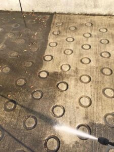 京都府の施設にて、黒ずんで滑りやすくなった駐車場スロープを高圧洗浄で清掃している様子。スリップ事故防止のためのメンテナンス風景