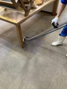 京都市伏見区の老人ホームで行われている絨毯（カーペット）の車載型クリーニング作業風景。専用機材を当てた部分だけ蓄積した黒ずみ汚れが落ち、本来の色を取り戻している劇的な様子